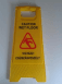 Csúszásveszélyre figyelmeztető kinyitható sárga műanyag tábla magyar és angol szöveggel összecsukva